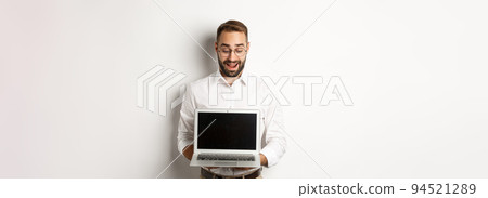 Excited businessman showing something on laptop screen, standing happy over white background Excited businessman showing something on laptop screen, standing happy over white background 94521289