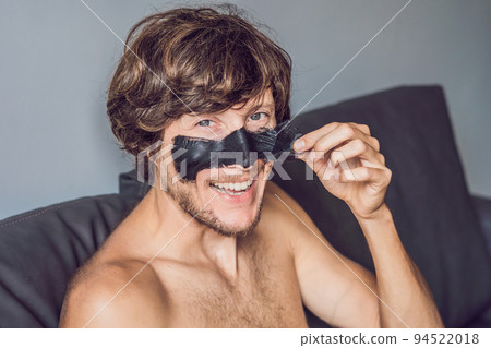 Happy man with black mask on the face. Photo man receiving spa treatments. Beauty Skin care concept Happy man with black mask on the face. Photo man receiving spa treatments. Beauty Skin care concept 94522018