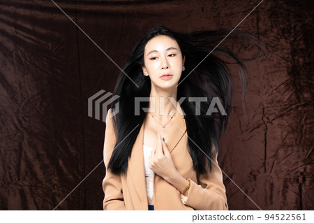 Haft body portrait of beautiful transgender 20s asian woman express feeling smiling confidently on brown background. Business Female smart look blazer has wind blow throw her hair in air, copy space Haft body portrait of beautiful transgender 20s asian woman express feeling smiling confidently on brown background. Business Female smart look blazer has wind blow throw her hair in air, copy space 94522561