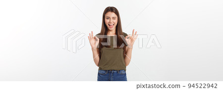 Happy young woman showing ok sign with fingers an winking isolated on a gray background. Happy young woman showing ok sign with fingers an winking isolated on a gray background. 94522942