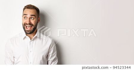 Close-up of happy and surprised man looking left with excitement, white background 94523344