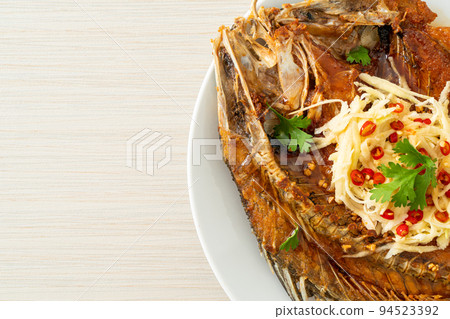 Fried Sea Bass Fish with Fish Sauce and Spicy Salad 94523392