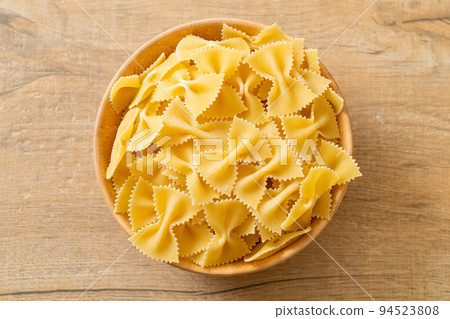 Dry uncooked farfalle pasta in bowl 94523808