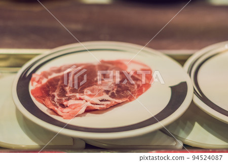 A conveyor with raw food on plates in a cafe 94524087