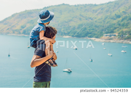 Father and son in the background of Promthep cape and Yanui beach. Phuket, Thailand. Traveling with children concept 94524359