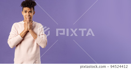 Portrait of anxious young worried hipster guy, 20s male being scared of what will happen next, scared getting sick, frowning and panicking, standing alarmed over purple background 94524412