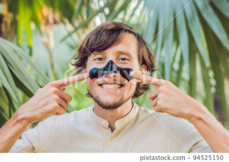 Happy man with black mask on the face. Photo of man receiving spa treatments. Beauty Skin care concept Happy man with black mask on the face. Photo of man receiving spa treatments. Beauty Skin care concept 94525150