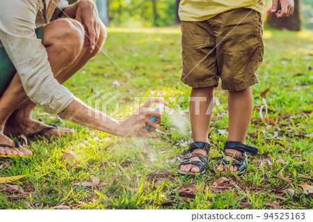 dad and son use mosquito spray.Spraying insect repellent on skin outdoor dad and son use mosquito spray.Spraying insect repellent on skin outdoor 94525163