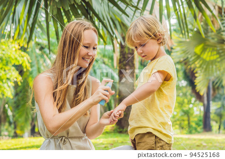 Mom and son use mosquito spray.Spraying insect repellent on skin outdoor 94525168