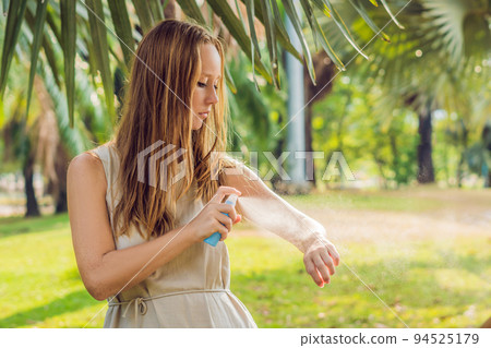 Woman spraying insect repellent on skin outdoor Woman spraying insect repellent on skin outdoor 94525179