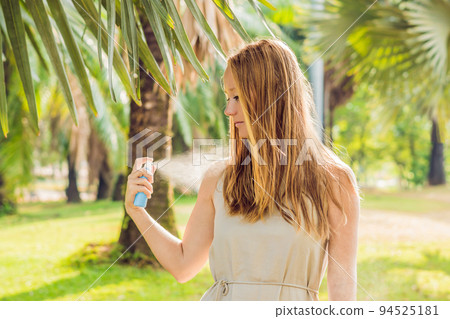Woman spraying insect repellent on skin outdoor 94525181