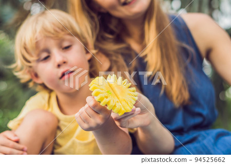 Mom and son had a picnic in the park. Eat healthy fruits - mango, pineapple and melon. Children eat healthy food Mom and son had a picnic in the park. Eat healthy fruits - mango, pineapple and melon. Children eat healthy food 94525662