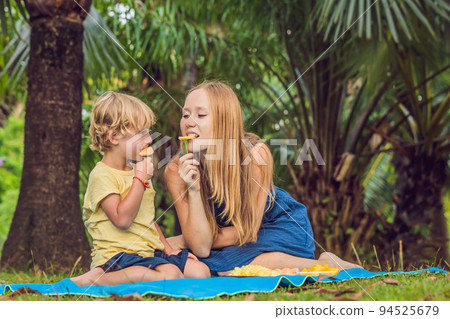 Mom and son had a picnic in the park. Eat healthy fruits - mango, pineapple and melon. Children eat healthy food 94525679
