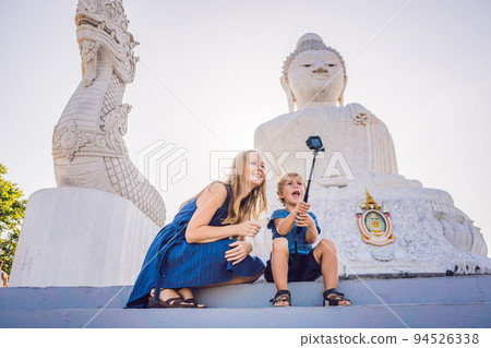 Mother and son tourists on the Big Buddha statue. Was built on a high hilltop of Phuket Thailand Can be seen from a distance Mother and son tourists on the Big Buddha statue. Was built on a high hilltop of Phuket Thailand Can be seen from a distance 94526338