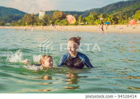 Woman swimming instructor for children is teaching a happy boy to swim in the sea Woman swimming instructor for children is teaching a happy boy to swim in the sea 94526414