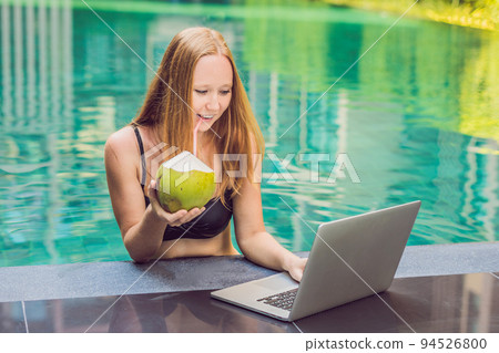 Young female freelancer sitting near the pool with her laptop in the hotel browsing in her smartphone. Busy at holidays. Distant work concept. Copy space for your text Young female freelancer sitting near the pool with her laptop in the hotel browsing in her smartphone. Busy at holidays. Distant work concept. Copy space for your text 94526800