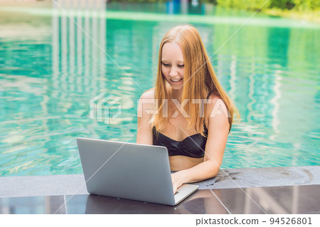 Young female freelancer sitting near the pool with her laptop in the hotel browsing in her smartphone. Busy at holidays. Distant work concept. Copy space for your text Young female freelancer sitting near the pool with her laptop in the hotel browsing in her smartphone. Busy at holidays. Distant work concept. Copy space for your text 94526801