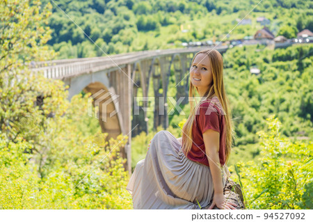Montenegro. Woman tourist in background of Dzhurdzhevich Bridge Over The River Tara. Travel around Montenegro concept. Sights of Montenegro Portrait of a disgruntled girl sitting at a cafe table 94527092