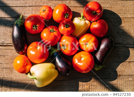 Organic food, harvest. Ripe vegetables red tomatoes sweet peppers eggplant lie on wooden table 94527230