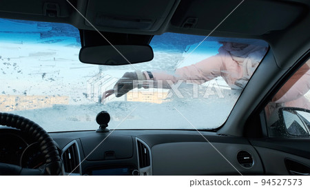 Young Woman Cleaning Frozen Windshield with Ice Scraper, Winter Season Young Woman Cleaning Frozen Windshield with Ice Scraper, Winter Season 94527573