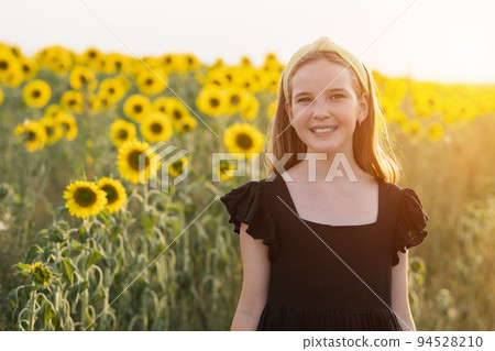 Teen girl stands demonstrating toothy smile by blurry field 94528210