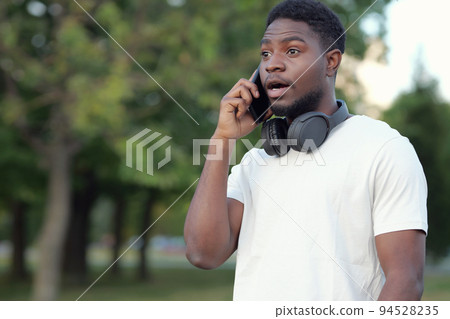 Black man talks on phone with friend discussing holiday Black man talks on phone with friend discussing holiday 94528235