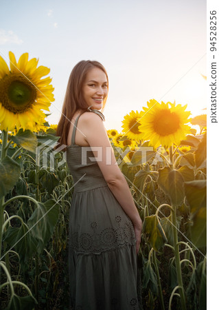 Woman in green dress walks past sunflower field... - Stock Photo [94528256]  - PIXTA