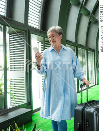 60多歲的亞洲熟年婦女微笑著站在身旁有手提箱行李袋和使用智能手機,適用於covid19疫情後旅行的概 60多歲的亞洲熟年婦女微笑著站在身旁有手提箱行李袋和使用智能手機,適用於covid19疫情後旅行的概 94529112
