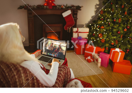 Caucasian santa claus on christmas laptop video call with african american family 94529602