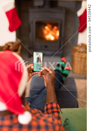 African american man making smartphone christmas video call with smiling senior father African american man making smartphone christmas video call with smiling senior father 94530442