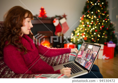 Caucasian woman on christmas laptop video call with diverse group of friends 94530472
