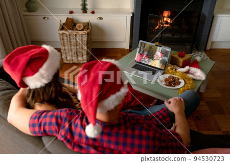 Caucasian couple in santa hats on christmas video call on laptop with senior parent Caucasian couple in santa hats on christmas video call on laptop with senior parent 94530723
