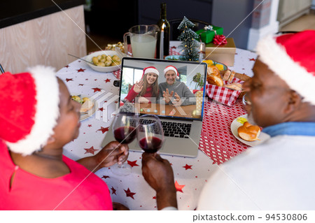 African american senior couple in santa hat with vine on christmas laptop video call with friends African american senior couple in santa hat with vine on christmas laptop video call with friends 94530806