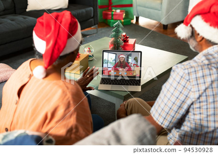 African american senior couple in santa hats on christmas laptop video call with friend African american senior couple in santa hats on christmas laptop video call with friend 94530928