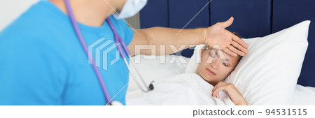 Male doctor in uniform checks temperature of patient lying in bed 94531515
