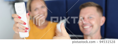 Married couple is holding handset and phone and thumbs up gesture in hotel room Married couple is holding handset and phone and thumbs up gesture in hotel room 94531528