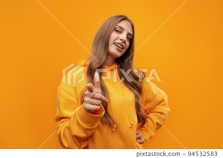 Young woman over yellow background points finger at you 94532583