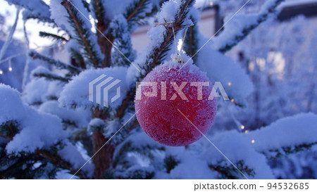 Christmas time atmosphere. Red Christmas ball hanging on a frost covered pine tree with copy space. 94532685