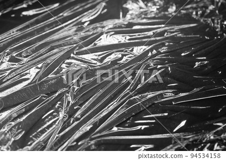 Reflecting light and shadow on creases and folds in black plastic sheeting Reflecting light and shadow on creases and folds in black plastic sheeting 94534158