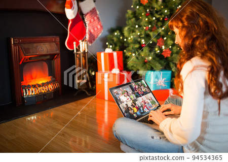 Caucasian woman on laptop christmas video call with smiling friends Caucasian woman on laptop christmas video call with smiling friends 94534365