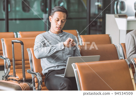 business man boring in airport waiting from flight delay late hours looking wrist watch and worried business man boring in airport waiting from flight delay late hours looking wrist watch and worried 94534509