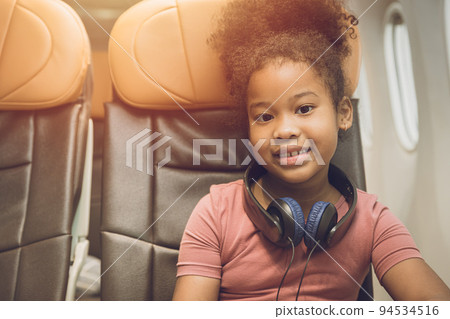 children traveling alone or unaccompanied minor. child girl fly travel sitting alone in flight cabin seat happy smile. 94534516