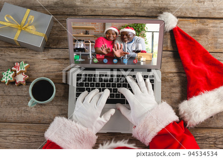 Santa claus making laptop christmas video call with smiling senior african american couple Santa claus making laptop christmas video call with smiling senior african american couple 94534534