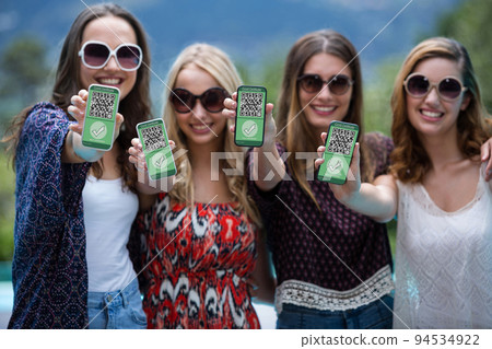 Group of female friends holding documents and smartphone with covid 19 vaccine passport Group of female friends holding documents and smartphone with covid 19 vaccine passport 94534922