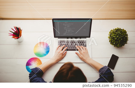 Caucasian female programmer with colour charts using tablet with coding on screen 94535290