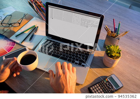 Hands of caucasian male programmer sitting at desk and using laptop with coding on screen 94535362