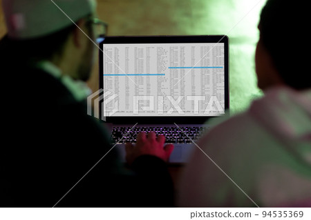 Back view of two diverse male colleagues using laptop with coding on screen 94535369