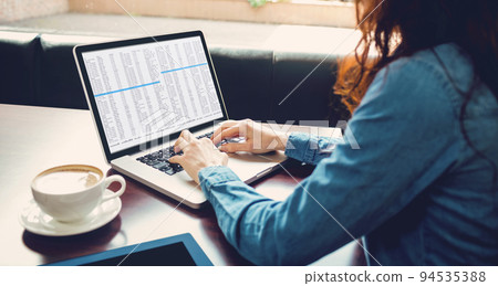 Midsection of caucasian female programmer sitting with coffee, using laptop with coding on screen 94535388