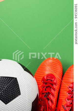 Image of orange football boots and football on green background with copy space Image of orange football boots and football on green background with copy space 94536091
