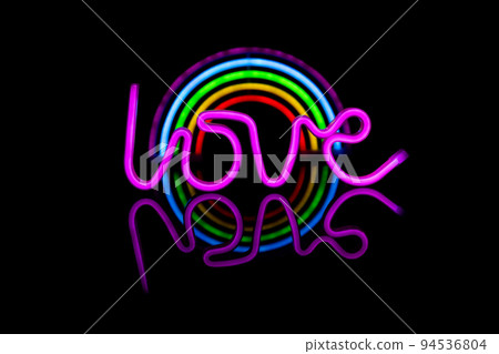 Image of vibrant neon love text and glow sticks forming rainbow over black background and copy space 94536804